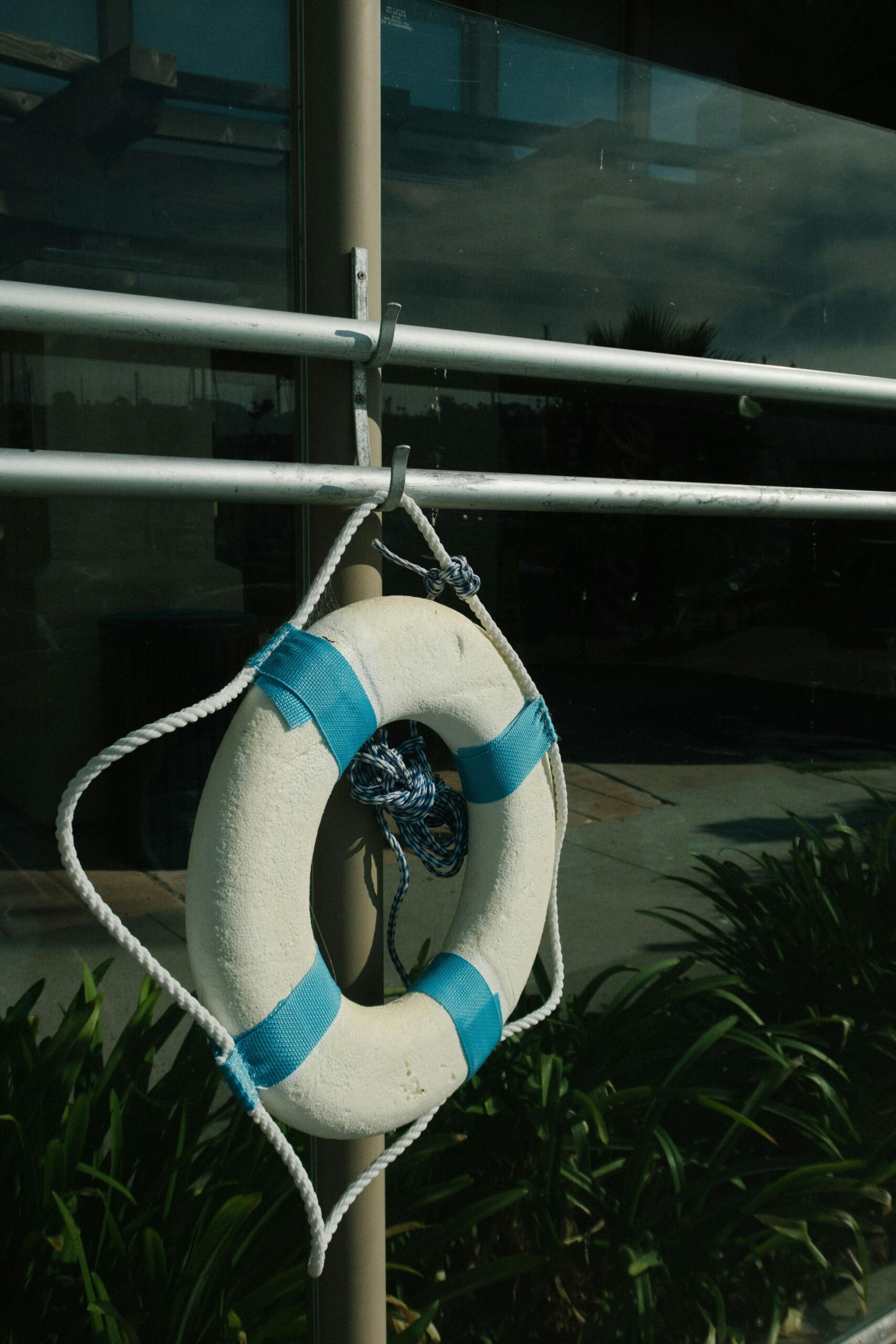 pexels-photo-2961949-2961949 A white lifebuoy with blue stripes hanging outside on a metal frame by a window.